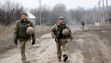 جنديان أوكرانيان يقومان بدورية في مستوطنة ترويتسكي في منطقة لوغانسك قرب خط المواجهة مع الانفصاليين (22 شباط 2022، أ ف ب). 