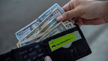 رجل يحمل محفظة في داخلها دولارات أميركية (أ ف ب). 