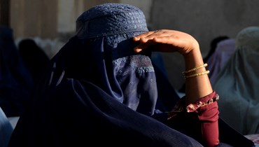 امرأة تنتظر مع اخريات خارج مكتب المفوضية السامية للأمم المتحدة لشؤون اللاجئين في قندهار لتلقي المواد غير الغذائية (8 آذار 2022، أ ف ب). 