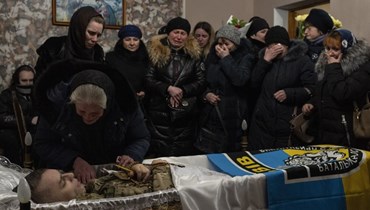 أقارب وأصدقاء يبكون الرقيب في الشرطة رومان روشيشين في قرية سوبوشين بضواحي لفيف غرب أوكرانيا (10 آذار 2022، ا ب). 