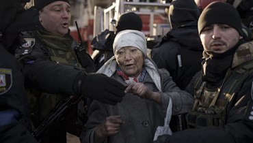 شرطيون يساعدون امرأة مسنة بعدما أنقذها رجال الإطفاء من داخل شقتها بعد قصف كييف (15 آذار 2022، أ ب). 