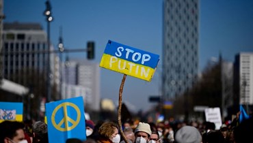 متظاهرون يرفعون في برلين لافتات كتب عليها "أوقفوا بوتين" خلال احتجاج على الغزو الروسي لأوكرانيا (13 آذار 2022، أ ف ب). 