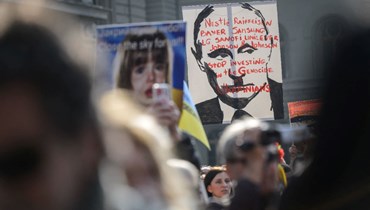 اشخاص يحملون لافتات خلال تظاهرة ضد الغزو الروسي لأوكرانيا بجوار مجلس النواب السويسري في برن (19 آذار 2022، أ ف ب).