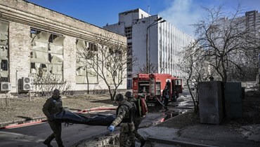 عناصر من خدمة الطوارئ العسكرية ينقلون جثة جندي أوكراني في منطقة معهد أبحاث، جزء من الأكاديمية الوطنية الأوكرانية للعلوم، بعد قصف في شمال غرب كييف (22 آذار 2022، ا ف ب). 