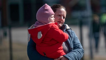 امرأة تعبر مع طفل الحدود عند المعبر الحدودي الأوكراني البولندي في ميديكا جنوب شرق بولندا (24 آذار 2022، ا ف ب). 
