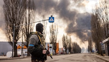 جندي أوكراني يقف بالقرب من مستودع مشتعل بعد أصابته بقذيفة روسية في ضواحي كييف (24 آذار 2022، ا ف ب). 
