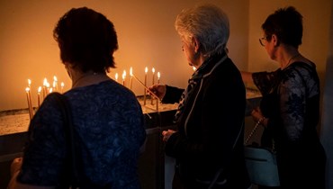 مسيحيون أرثوذوكس من أصول أوكرانيّة يعيشون في اليونان يضيئون الشموع خلال حفل عيد الفصح الأرثوذكسي في كنيسة في أثينا في 23 نيسان 2022 (أ ف ب).