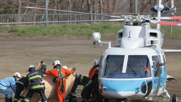 عناصر انقاذ يحاولون إخفاء حمالة عن وسائل الإعلام أثناء قيامهم بنقل شخص من سيارة إسعاف إلى مروحية (أ ف ب).