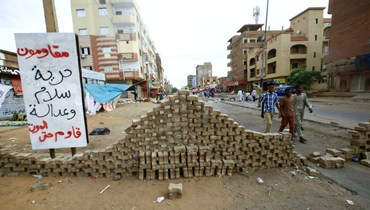 متظاهرون سودانيون يقفون خلف حواجز على الطرق أثناء مشاركتهم في اعتصام مناهض للجيش (أ ف ب).