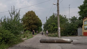 أشخاص ينظرون الى قطعة من صاروخ سقطت في كراماتورسك (11 آب 2022، أ ف ب). 