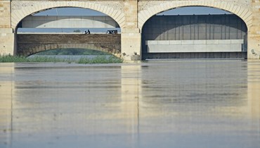 سائقو دراجات يمرون على سد سوكور وسط فيضانات في سوكور في إقليم السند (28 آب 2022، أ ف ب). 