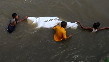 أشخاص يسحبون جثة ضحية قضت في غرق قارب في نهر كاروتوا بالقرب من بلدة بودا في بنغلادش (26 أيلول 2022، أ ف ب). 