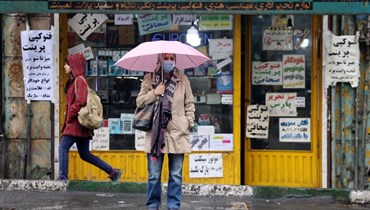 امرأة تنتظر سيارة أجرة في ساحة انقلاب في طهران (5 ك1 2022، أ ف ب). 