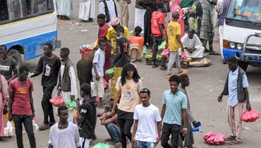 أشخاص يمشون في محطة للحافلات في بورتسودان (23 أيار 2023، أ ف ب).