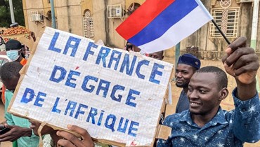 محتجون يحملون لافتة مناهضة لفرنسا خلال تظاهرة في نيامي (3 آب 2023، أ ف ب). 