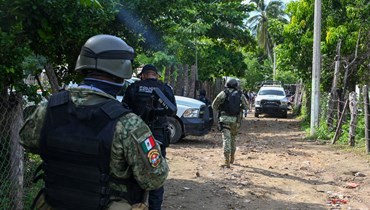 عناصر من قوات الأمن انتشروا في المنطقة التي قُتل فيها ما لا يقل عن 11 شرطيا في كمين نصبته مجموعات إجرامية في كويوكا دي بينيتيز بولاية غيريرو (13 ت1 2023، أ ف ب). 