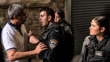 شرطي إسرائيلي يتجادل مع رجل خلال منع مصلين مسلمين من دخول مجمع المسجد الأقصى في البلدة القديمة بالقدس (27 ت1 2023، أ ف ب). 