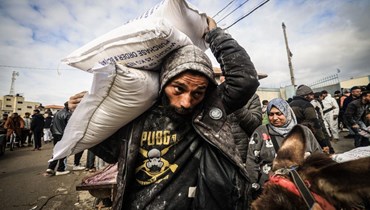 نازحون فلسطينيون يتلقون مساعدات غذائية في مركز للأونروا في رفح بجنوب قطاع غزة (28 ك2 2024، أ ف ب). 