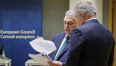 أوربان (الى اليسار) يعرض وثائق على رئيس وزراء سلوفاكيا روبرت فيكو قبل بدء اجتماع المجلس الأوروبي في المقر الأوروبي في بروكسيل (1 شباط 2024، أ ف ب). 