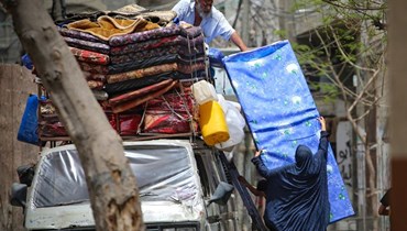 فلسطينيون يحملون مركبة بالمراتب خلال انتقالهم إلى مناطق أكثر أمانا في رفح بجنوب قطاع غزة (10 ايار 2024، أ ف ب). 