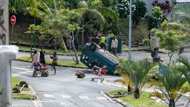 أشخاص تجمعوا بالقرب من سيارة مقلوبة في منطقة موتور بول في توبان بنوميا (16 ايار 2024، أ ف ب). 
