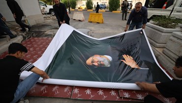تعليق صورة ضخمة للرئيس الإيراني الراحل إبراهيم رئيسي خارج سفارة الجمهورية الإسلامية في بغداد (أ ف ب). 
