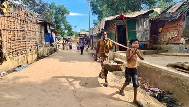 لاجئون من الروهينغا يمشون على طريق في مخيم للاجئين الروهينغا في أوخيا بمنطقة كوكس بازار جنوب شرق بنغلادش (24 ايار 2024، أ ف ب).