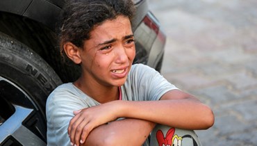 فتاة فلسطينية تبكي وسط معاناة النزوح في دير البلح (أ ف ب).