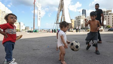 أطفال نزحوا إلى ساحة الشهداء هرباً من القصف الإسرائيلي (أ ف ب). 